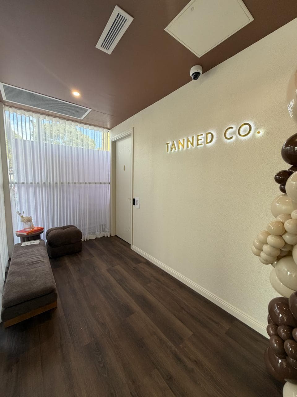 Inside a Tanned Co. studio: the lit Tanned Co. sign and waiting area